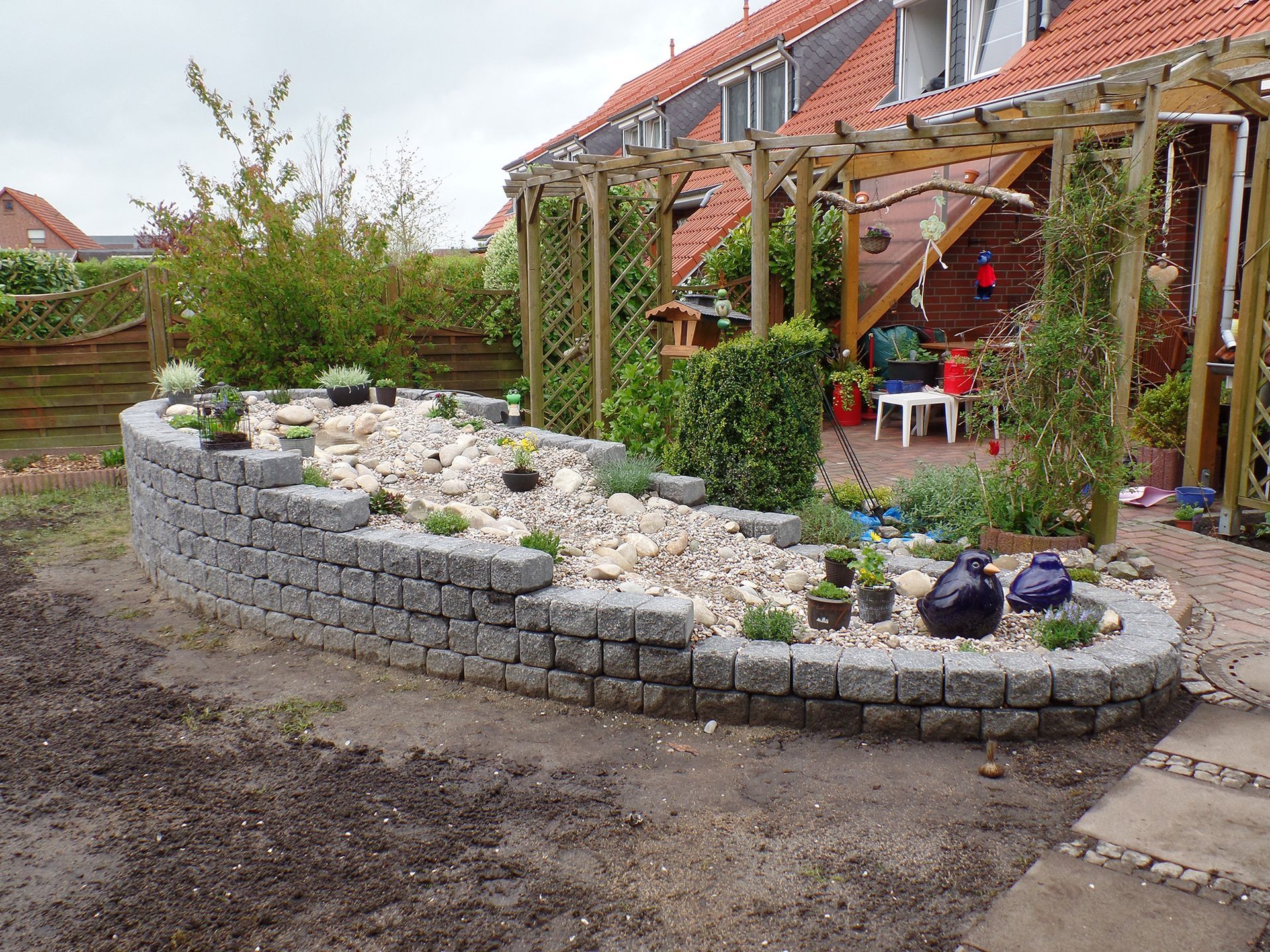 Ein Garten mit einer Pergola und einer Backsteinmauer