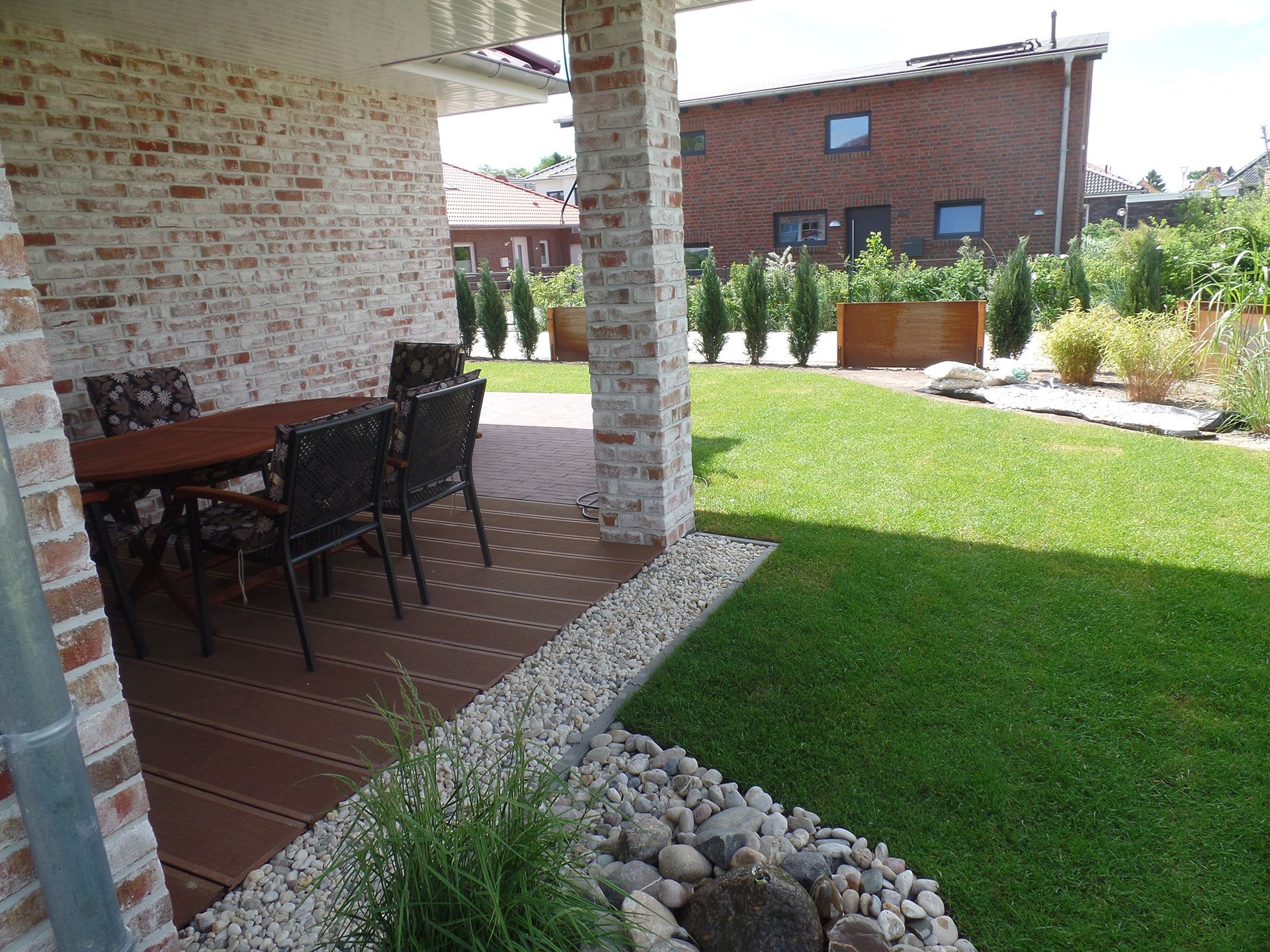 Eine Terrasse mit Tisch und Stühlen im Hinterhof eines Hauses.