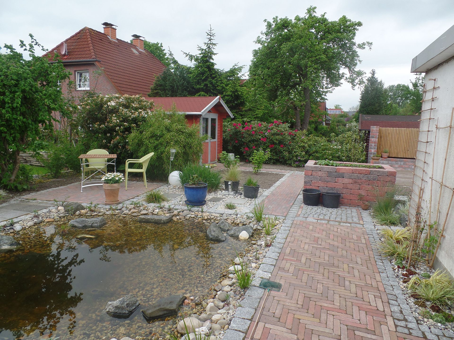 Ein Garten mit einem Teich und einem Ziegelweg