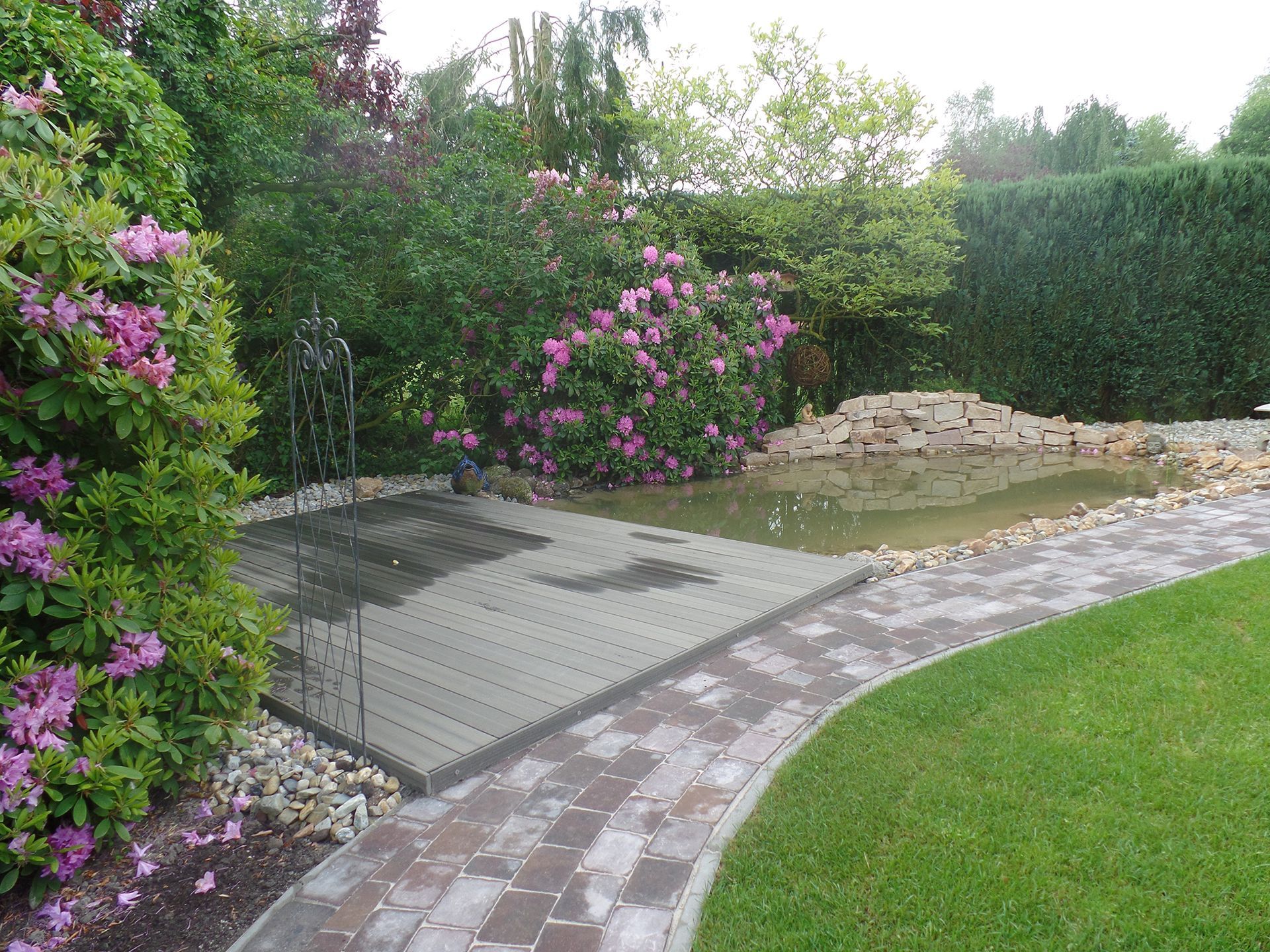 Ein Ziegelweg führt zu einem Teich in einem Garten