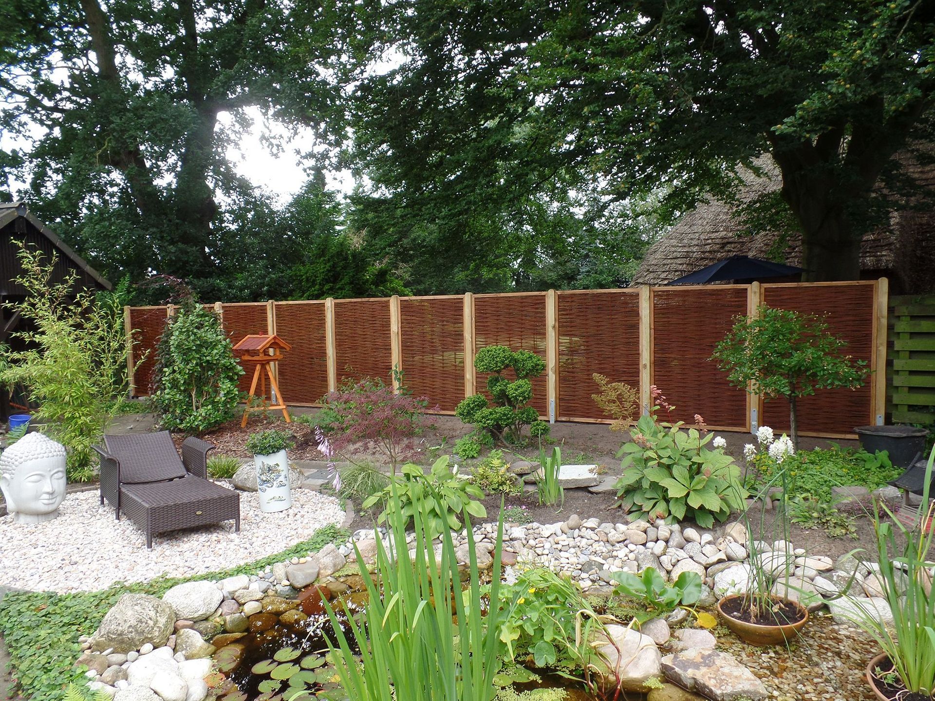 Ein Garten mit Holzzaun und Teich