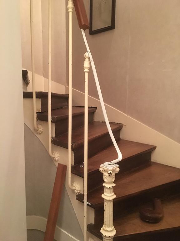 Escalier en bois avec rampe blanche, marches marron et murs aux tons neutres.