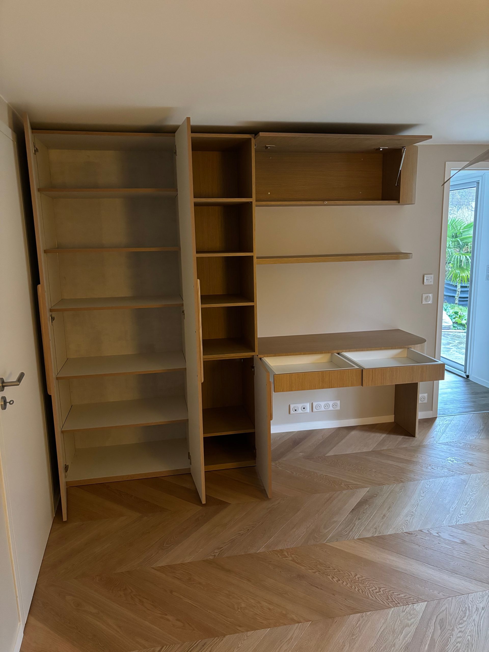 Étagère en bois encastrée contre un mur beige, comprenant un bureau et une bibliothèque.