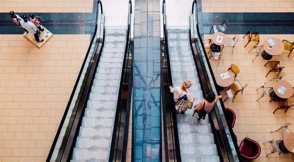 Ein paar Leute fahren in einem Einkaufszentrum auf einer Rolltreppe.