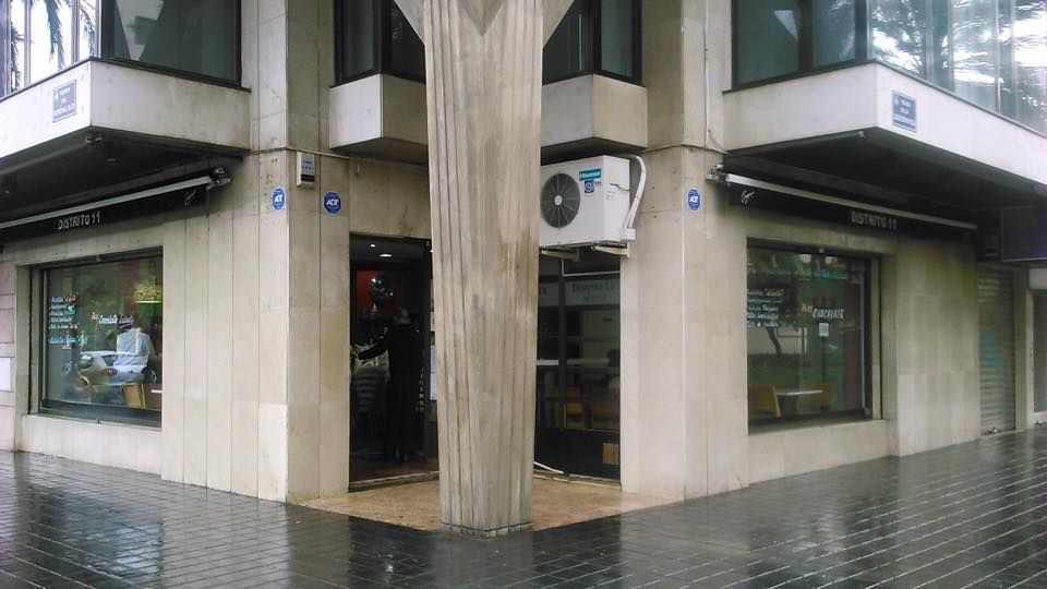 Fachada antigua y sucia con un bar y una columna en el medio