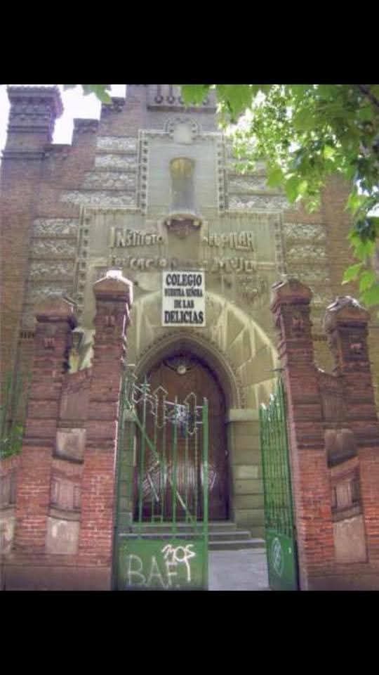 The ornate, brick-and-stone entrance to the Colegio Santa María de las Delicias, marked by a green gate and graffiti.