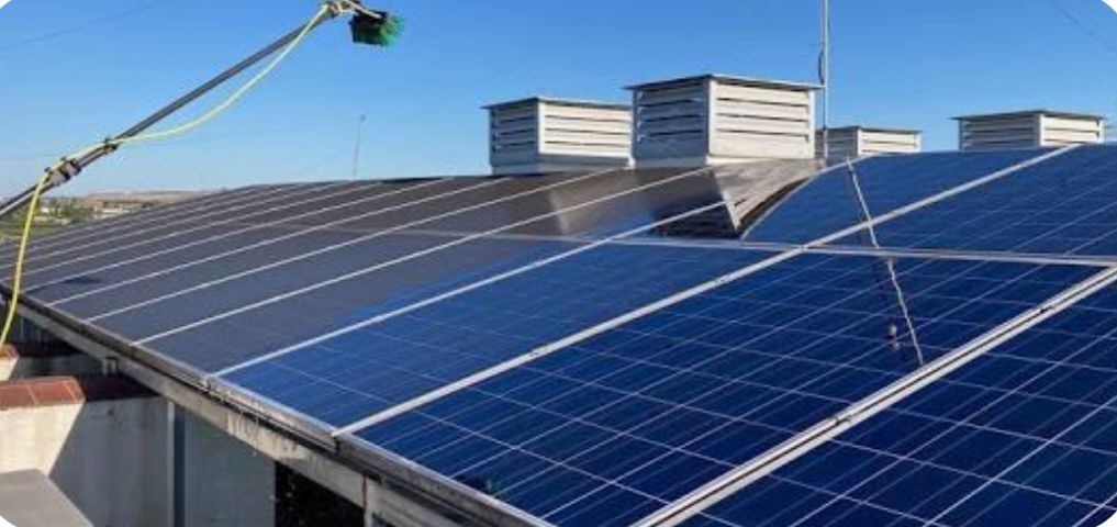Un tejado cubierto de paneles solares bajo un cielo azul despejado, con unidades de ventilación visibles al fondo.