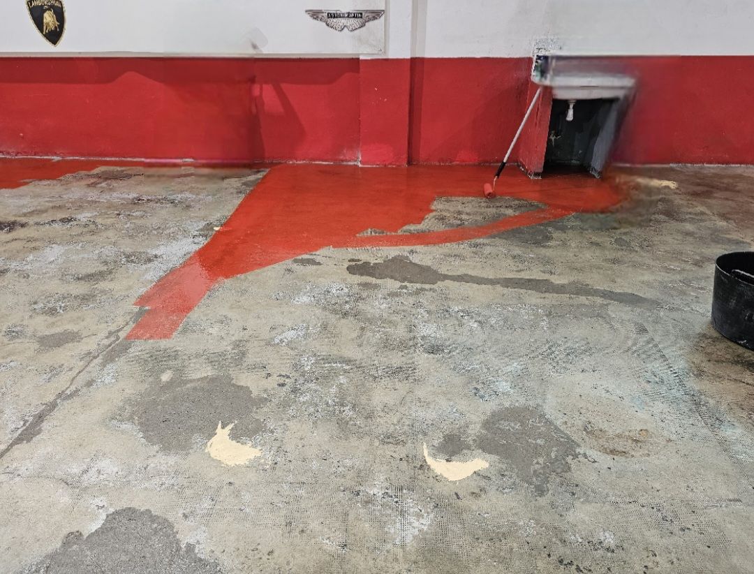 Suelo del garaje con parte pintada en rojo y otra sin terminar