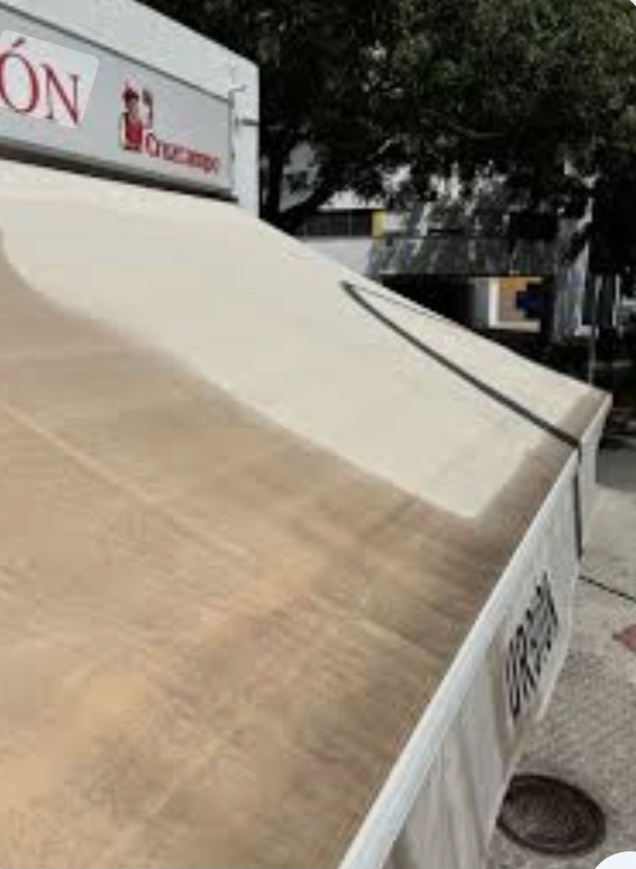 Un toldo retráctil de color claro para una cafetería al aire libre, parcialmente sombreado, con un logotipo y la palabra parcial 