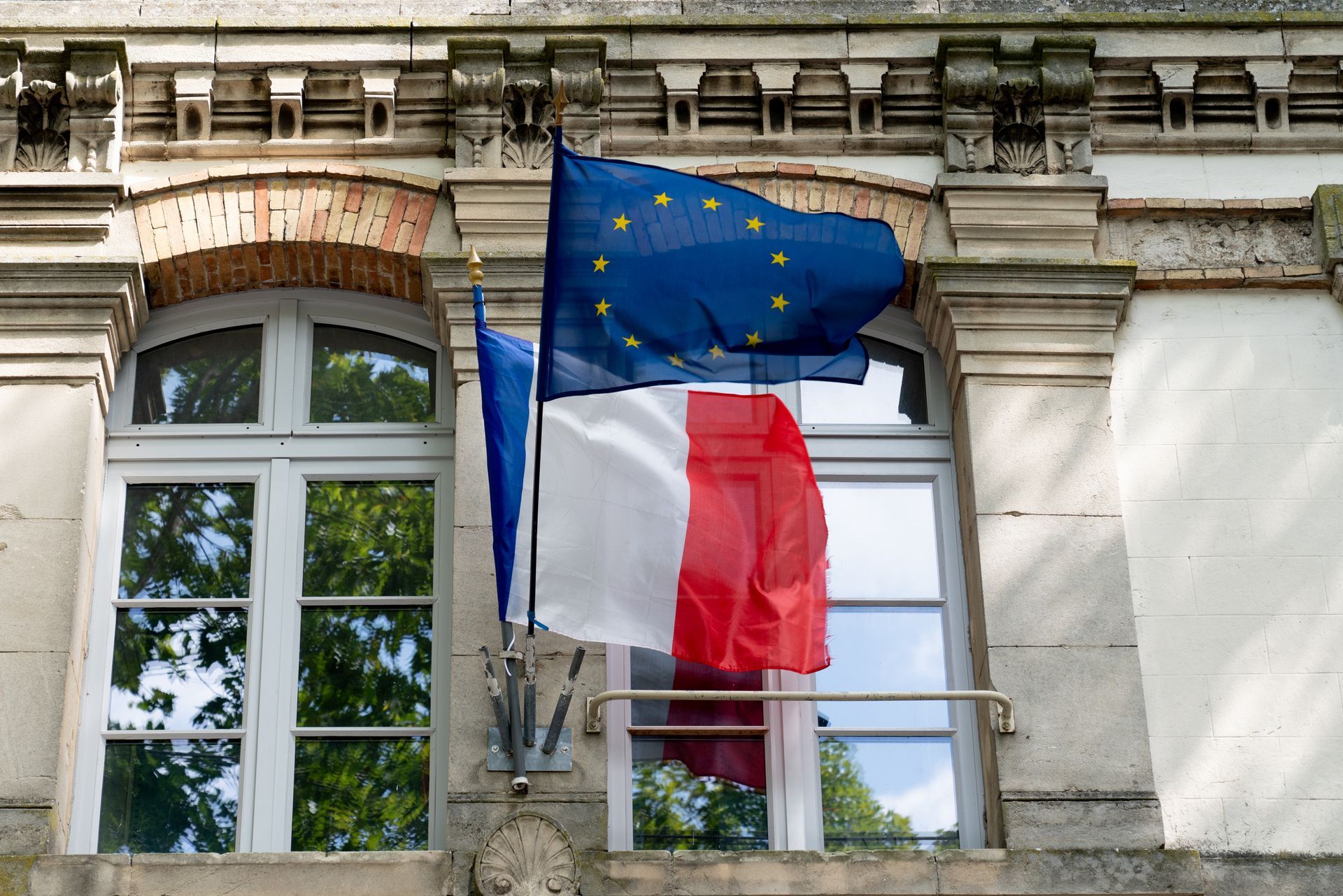 Façade d'un bâtiment administratif avec un drapeau français et un drapeau de l'union européenne