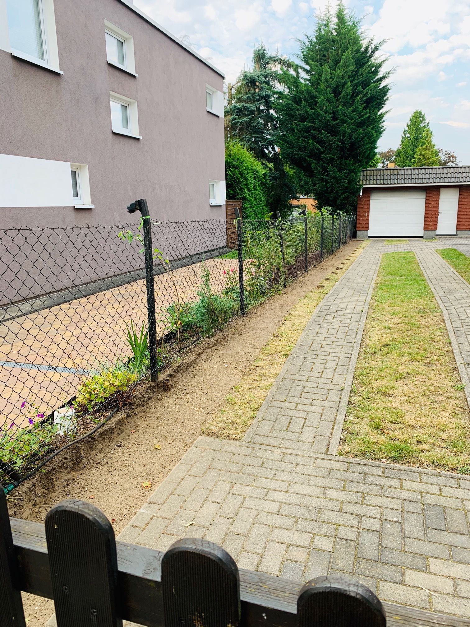 Ein Wohngebiet mit einer Auffahrt und einem Haus, einem Zaun und einer Garage, mit teilweisem Blick auf die Auffahrt.
