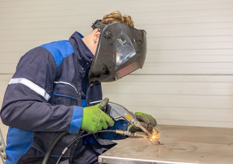 Ein Mann mit Schweißhelm schweißt ein Stück Metall.