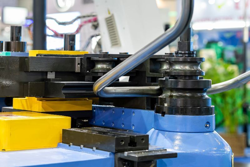 In einer Fabrik biegt eine Maschine ein Metallrohr.