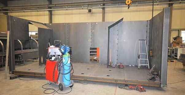 Große Metallwände auf einer Plattform stehen in einer Fabrikhalle