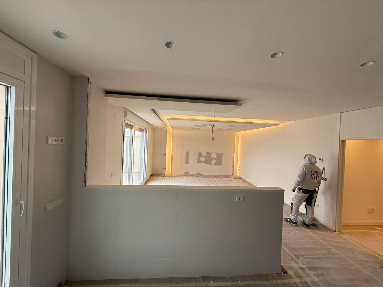 Persona con traje de protección pintando una habitación interior.