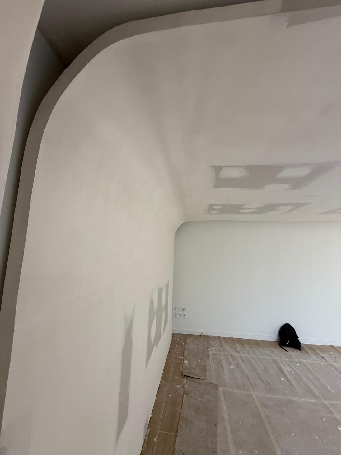 Paredes blancas en una habitación, una con una esquina curva, paneles de yeso sin terminar
