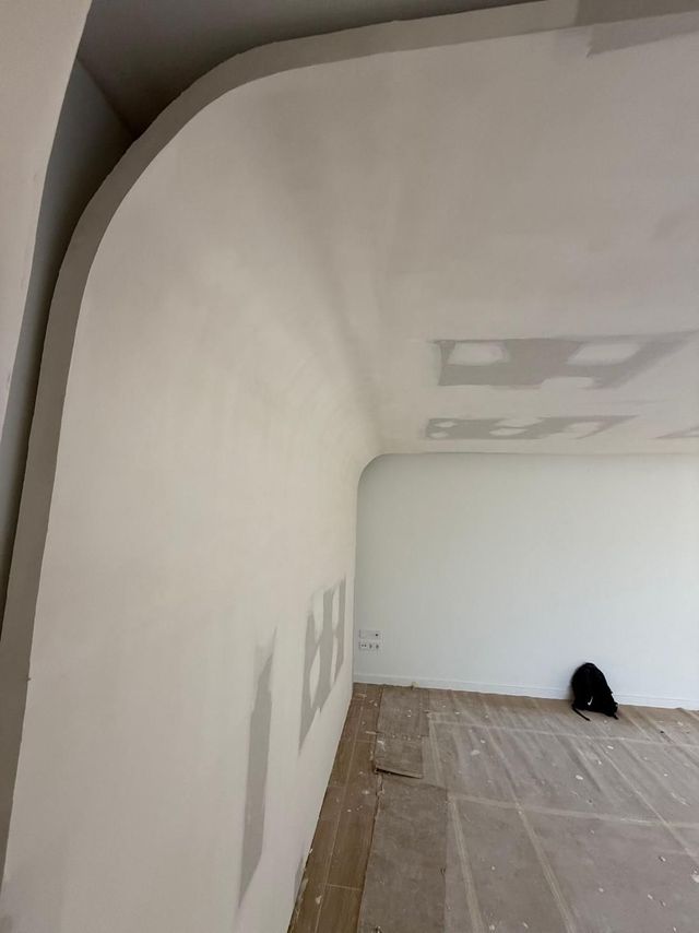 Paredes blancas en una habitación, una con una esquina curva, paneles de yeso sin terminar