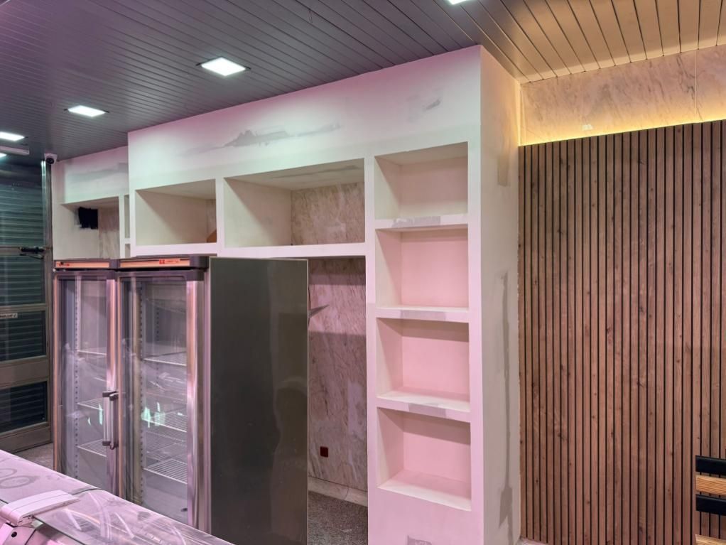 Interior con refrigeradores de acero inoxidable, estantes empotrados y pared de listones de madera