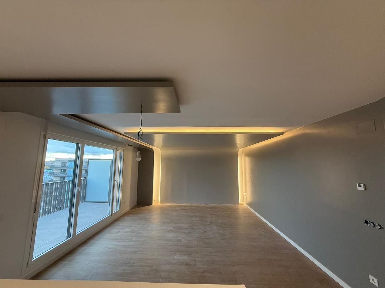 Habitación moderna con puerta corrediza de cristal, iluminación empotrada y suelo de madera.