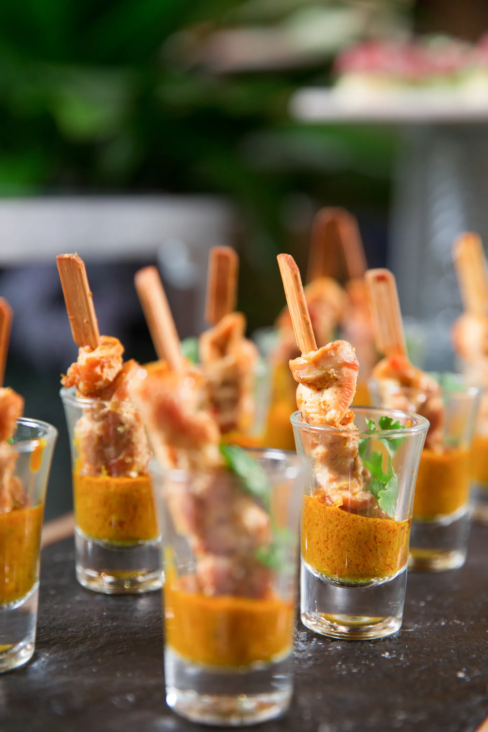 Aperitivos: Pollo en brocheta en vasos de chupito relleno de salsa de naranja. Brochetas de madera y hierbas frescas.