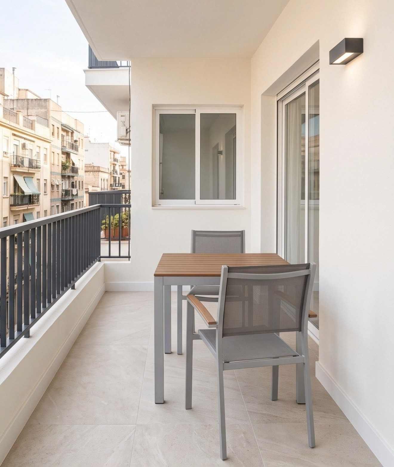 Balcón de un apartamento moderno con una mesita, dos sillas y vistas a la ciudad