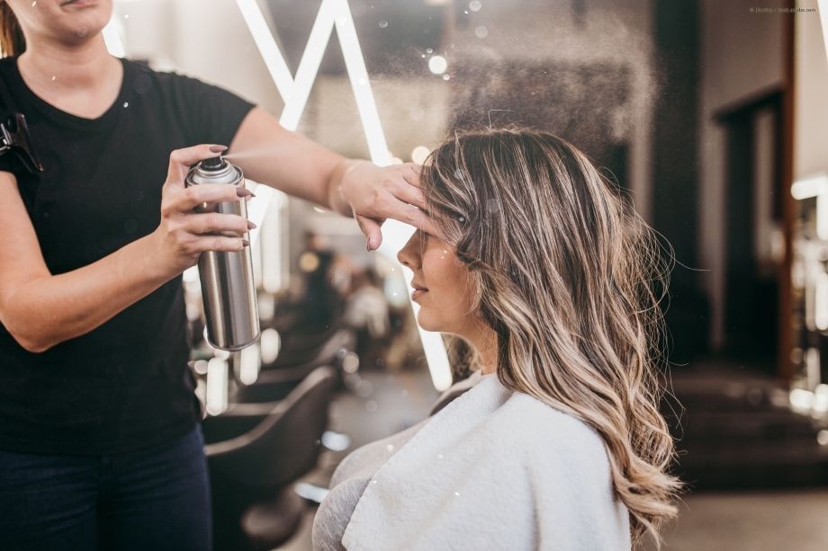 Eine Frau lässt sich in einem Salon von einem Friseur die Haare machen.