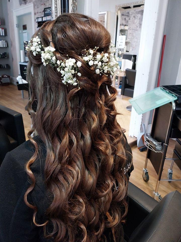 Eine Frau mit langen lockigen Haaren trägt einen Blumenkranz im Haar.