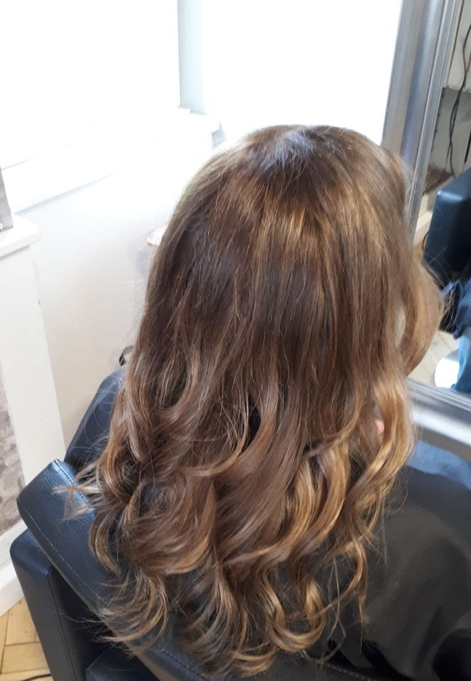 Eine Frau sitzt in einem Friseursalon auf einem Stuhl und frisiert.