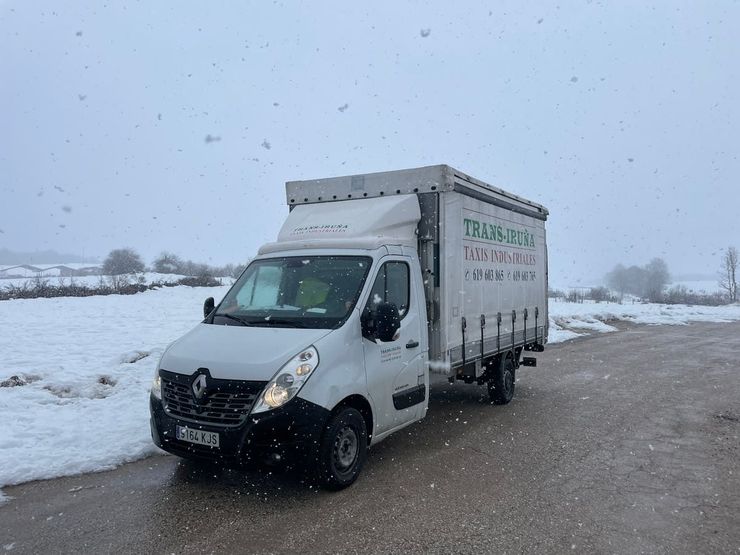 Camión blanco estacionado al costado de una carretera nevada en un paisaje invernal.