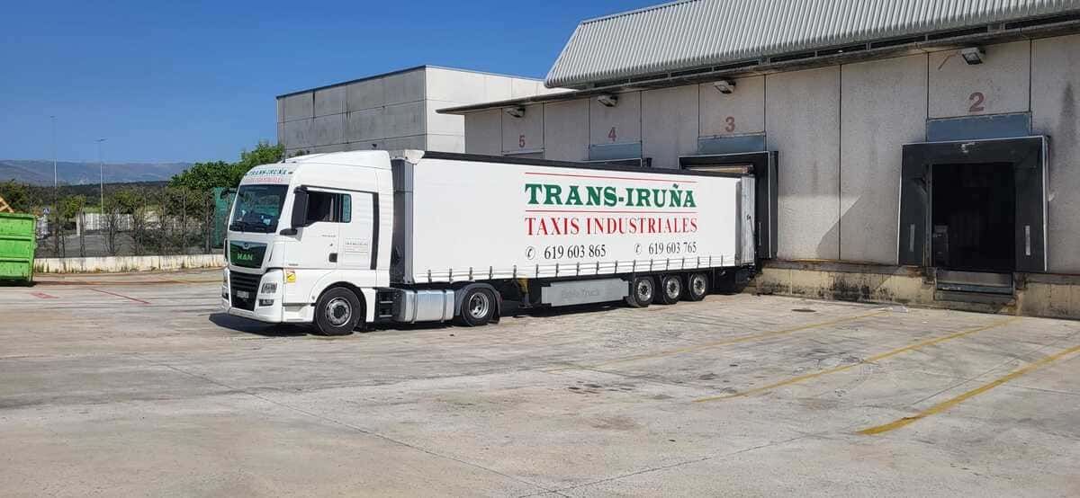 Camión blanco estacionado junto a un muelle de carga en un patio industrial.