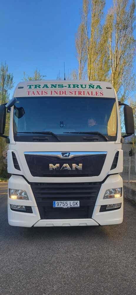 Camión industrial MAN blanco estacionado en una carretera bajo un cielo azul, vista frontal.
