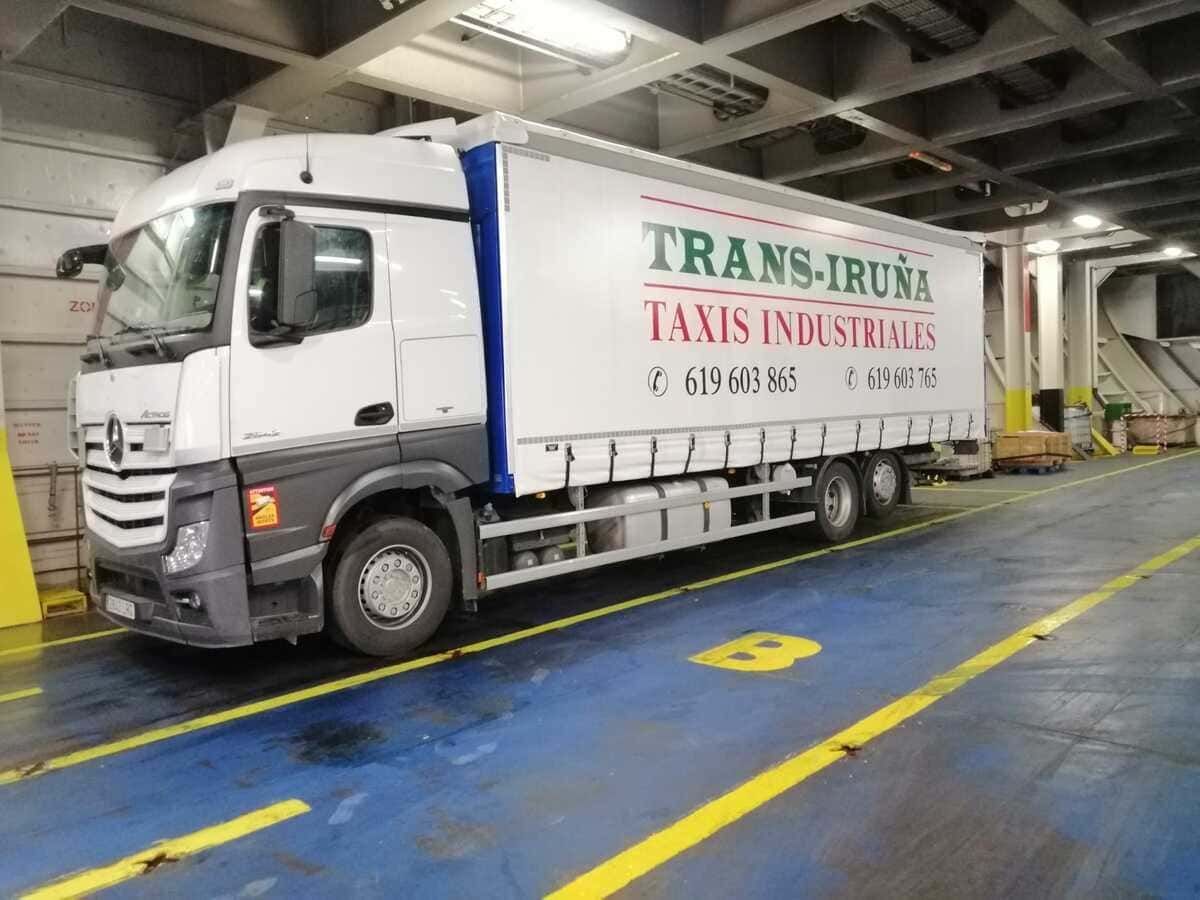 Camión de mudanzas blanco con la inscripción “TRANS-IRUN TAXIS INDUSTRIALS” estacionado en una zona de carga interior.