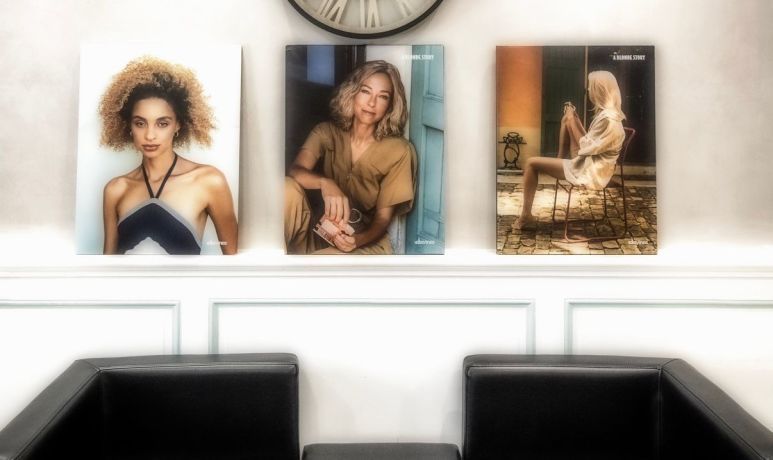 Trois portraits de mode accrochés au-dessus de chaises noires sur un mur blanc.
