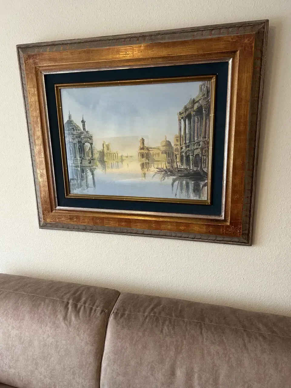 A framed painting hangs on a wall above a couch