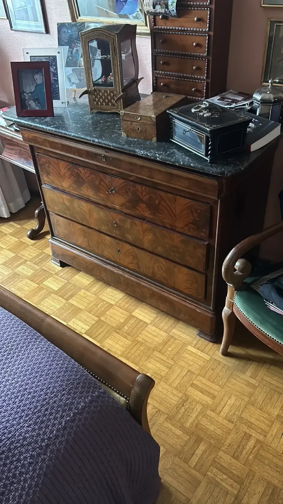There is a dresser in the middle of the room next to a bed.