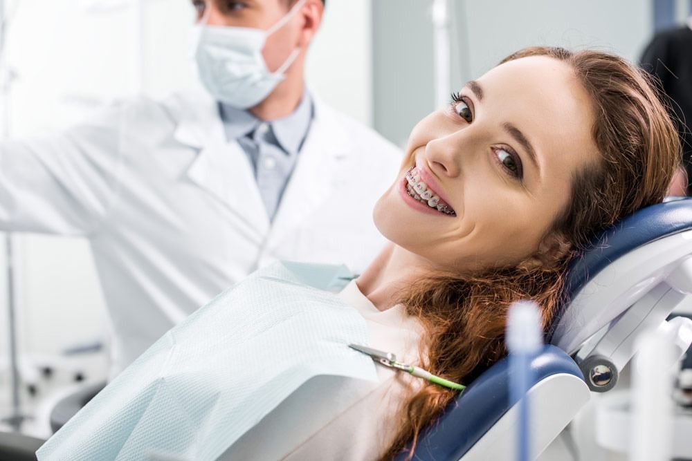 Una mujer sonríe mientras está sentada en una silla dental.