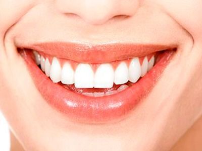 Un primer plano de la sonrisa de una mujer con dientes blancos y labios rojos.