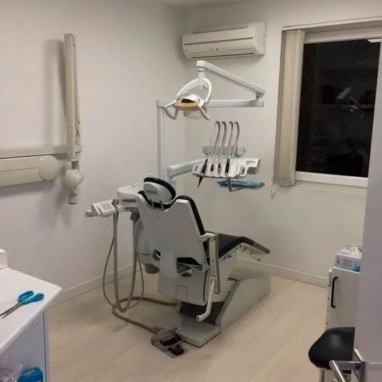 Un consultorio dental con un sillón dental y una ventana.