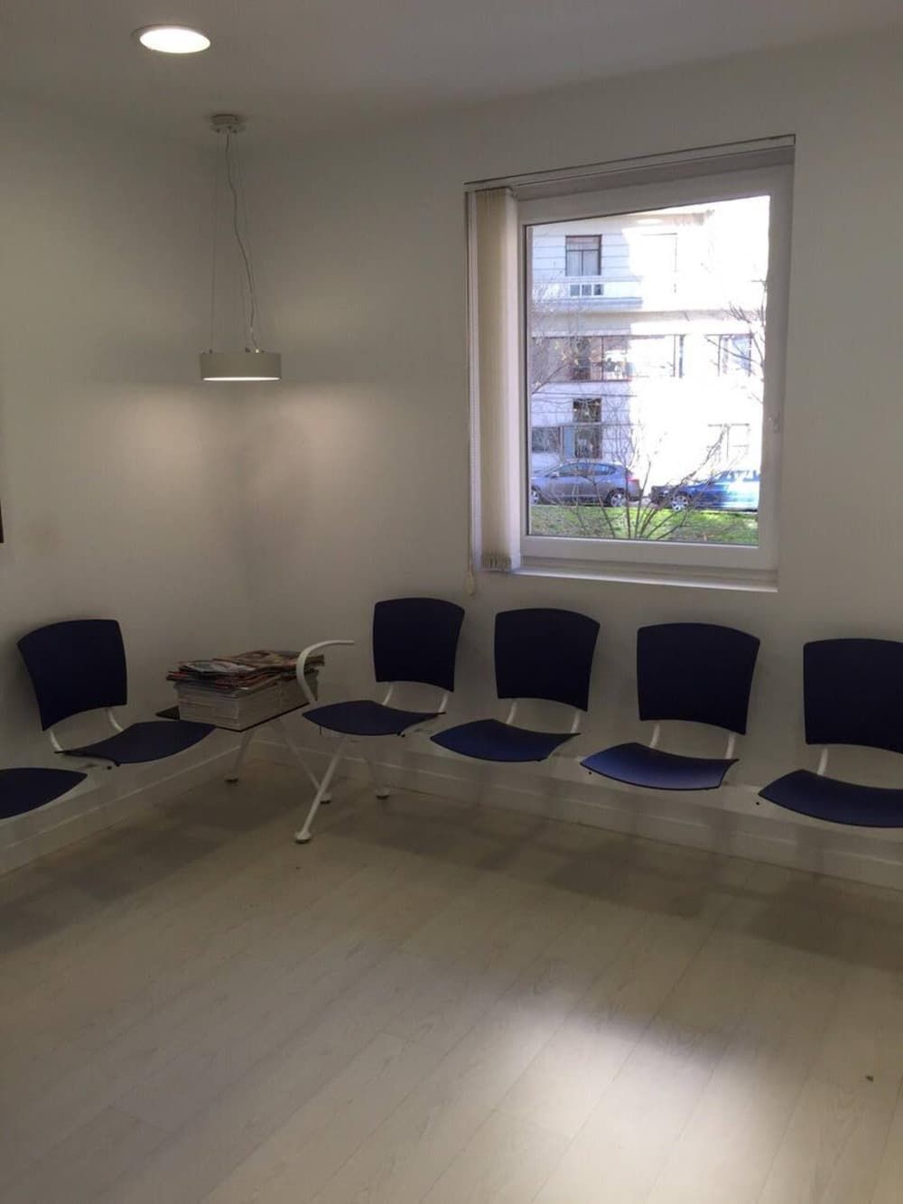 Una sala de espera con sillas azules y una ventana.