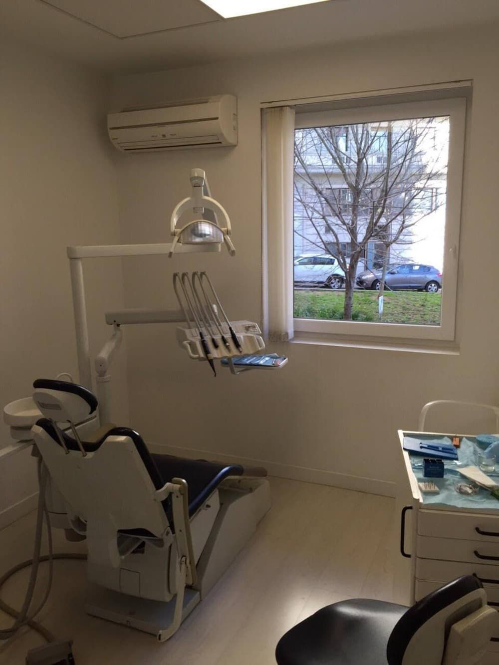 Un consultorio dental con un sillón dental y una ventana.