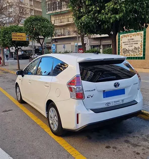 Un Toyota Prius blanco está estacionado al costado de la carretera.