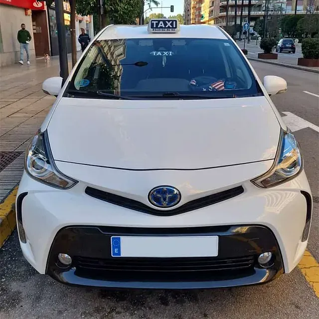 Un taxi blanco está estacionado al costado de la carretera.