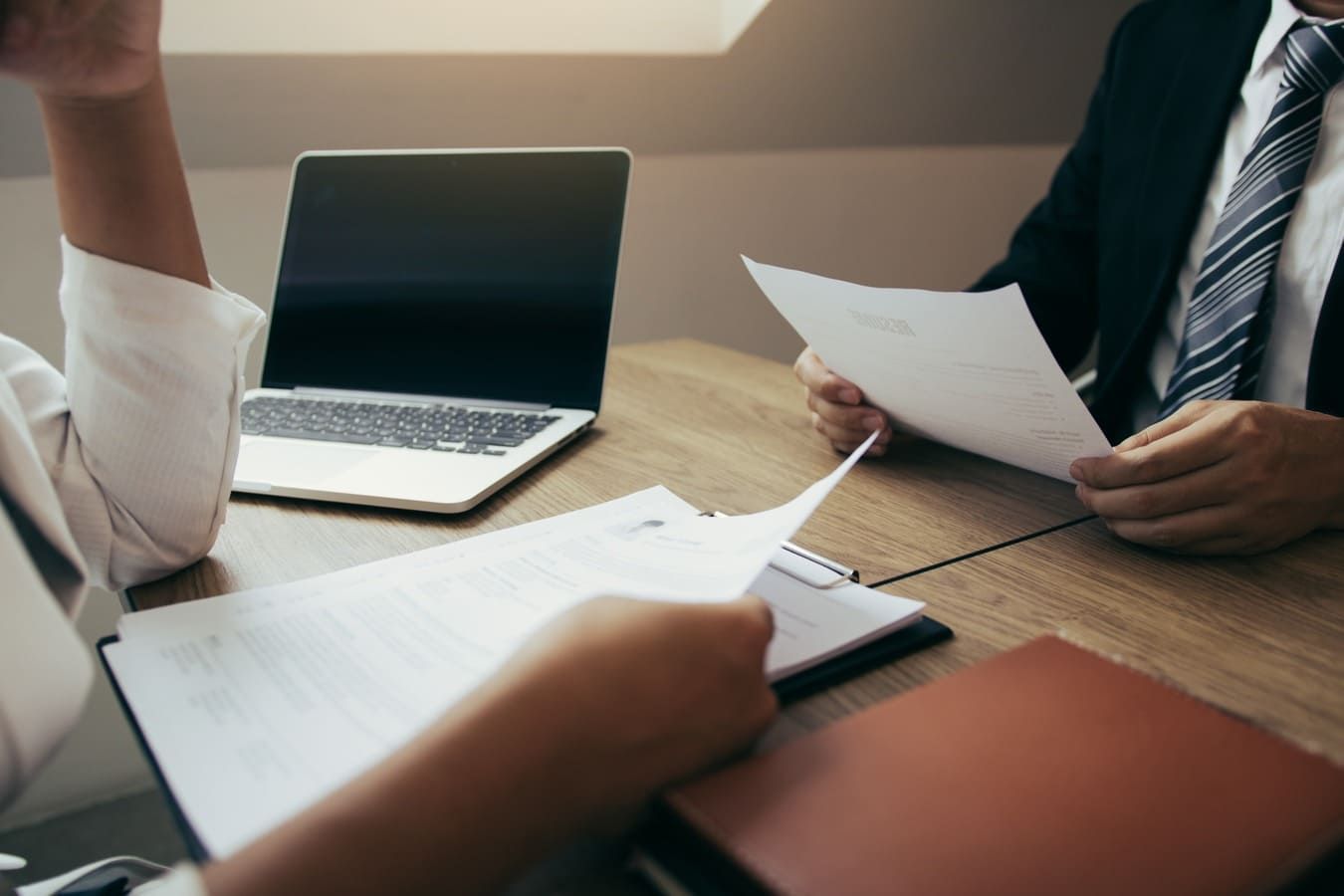 Un hombre y una mujer están sentados en una mesa con papeles y una computadora portátil.