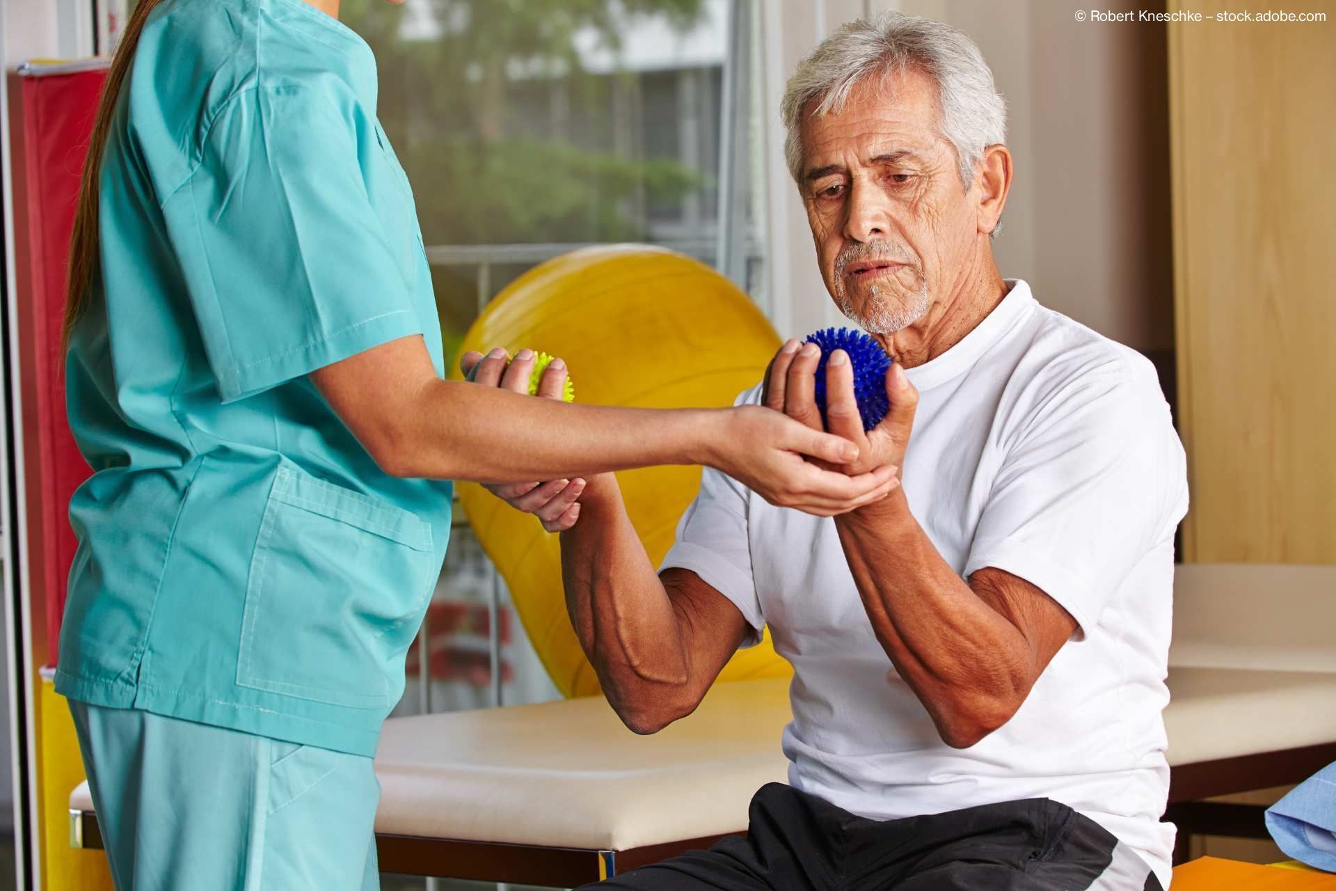 Physiotherapeut hilft einem älteren Mann bei einer Rehabilitationsübung mit Ball.