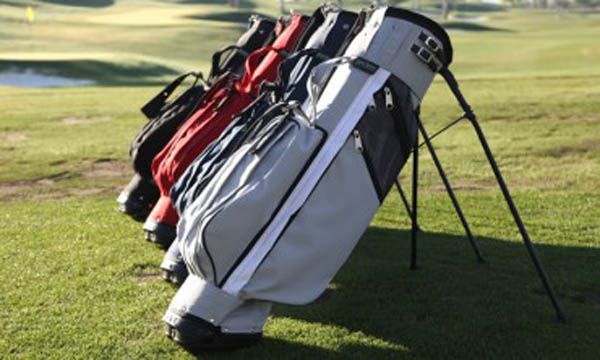 Una fila de bolsas de golf están alineadas en un campo de golf