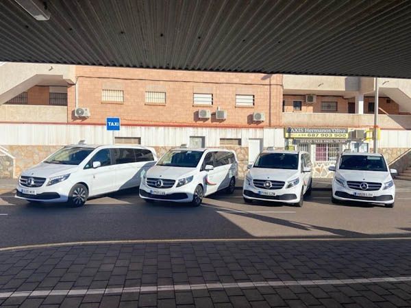 Una fila de furgonetas blancas están estacionadas frente a un edificio.