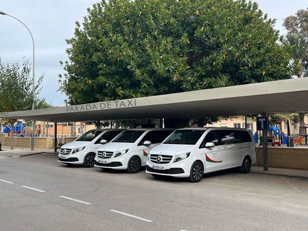 Una fila de furgonetas blancas están estacionadas bajo un toldo.
