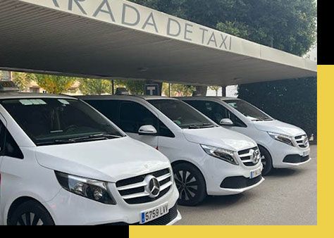 Una fila de furgonetas blancas están estacionadas frente a un edificio.