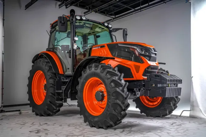 Tractor naranja y negro en un estudio, visto desde la parte frontal izquierda sobre un fondo blanco.