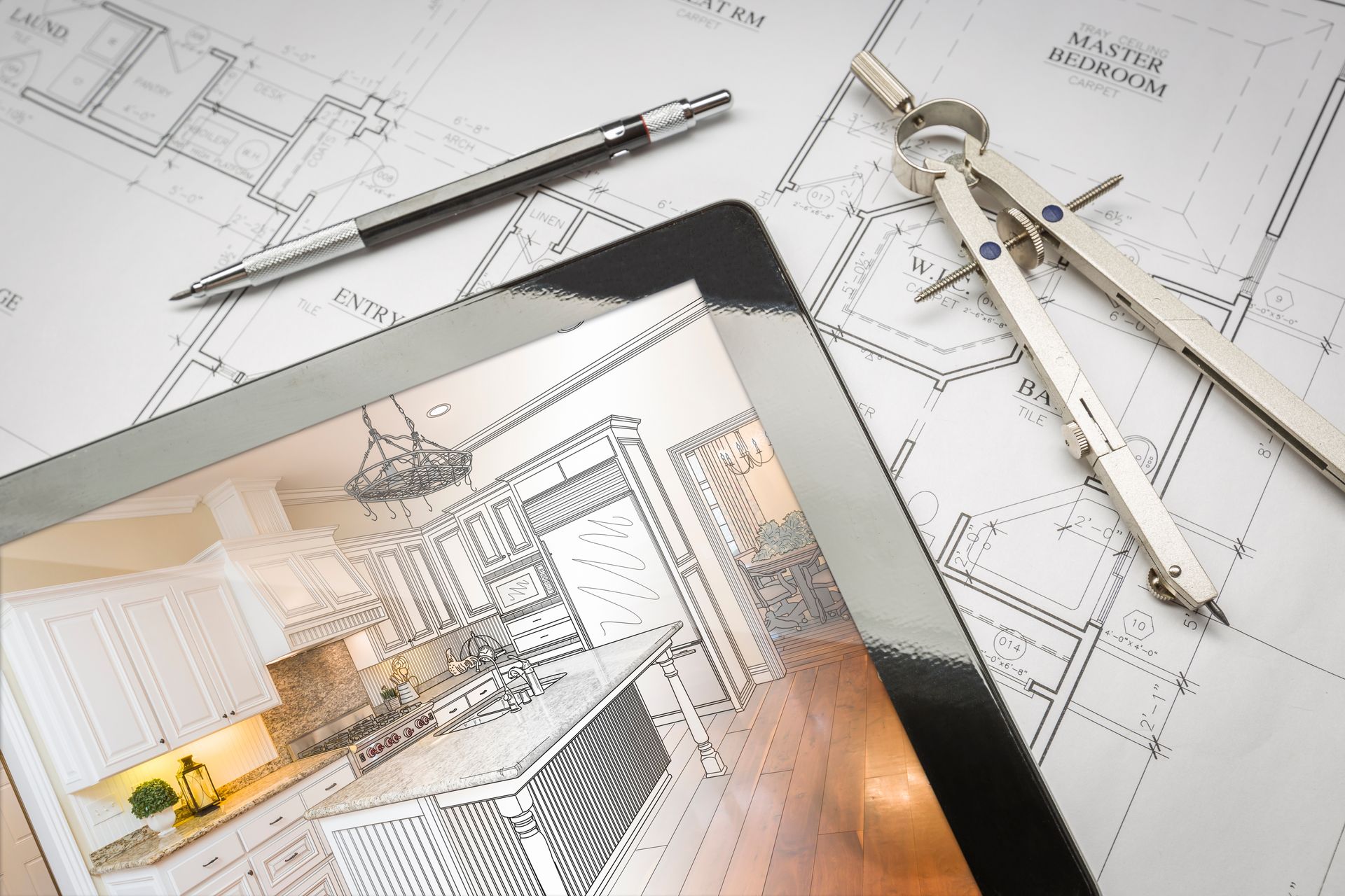 Plan architectural avec outils de dessin et une tablette montrant un croquis d'aménagement intérieur.